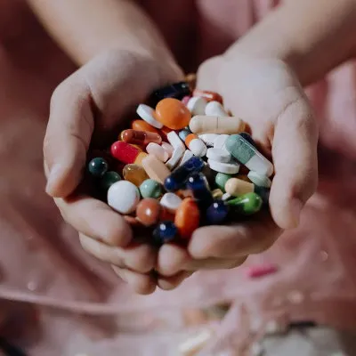 A child's hands cupping an absurd quantity of unmarked pills