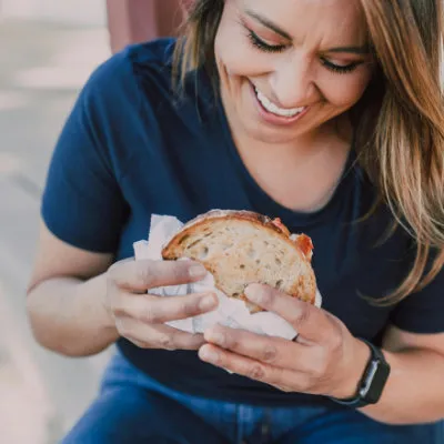 Woman smiling at a sandwich in her hands